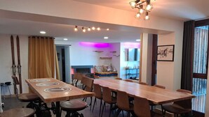 A modern dining area with a long wooden table and multiple chairs, a bar stool, and a hanging light fixture. - Spacious renovated apartment in center with balcony - 14p, pets allowed (Plagne Bellecôte)