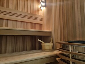 Un sauna en bois avec un banc, un seau et une plaque nominative.