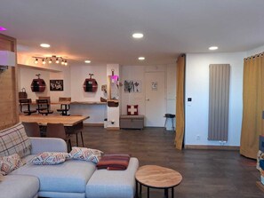 Una sala de estar moderna con un sofá, una mesa de comedor y una zona de cocina al fondo.