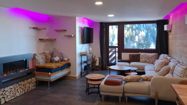 A cozy living room with a fireplace, sofa, and a TV mounted on the wall. - Spacious renovated apartment in center with balcony - 14p, pets allowed (Plagne Bellecôte)
