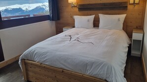 A bedroom with a wooden headboard, white bedding, and two bedside lamps. - Spacious renovated apartment in center with balcony - 14p, pets allowed (Plagne Bellecôte)