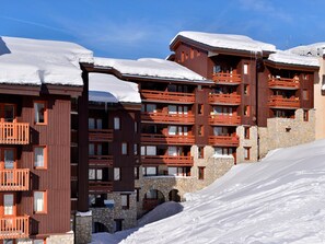 A multi-story hotel with balconies and stone walls, surrounded by snow.