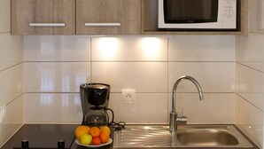 Una cocina equipada con cafetera, lavamanos y microondas.