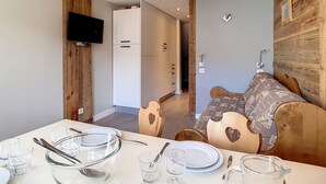 A compact living space with a dining area, kitchenette, and a TV mounted on the wall. - Comfortable duplex 5 pers · Ski-in/Ski-out · Balcony (Les Menuires)