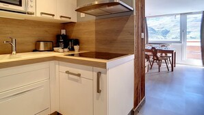 A modern kitchen with white cabinets, a stainless steel range hood, and a wooden backsplash. - Comfortable duplex 5 pers · Ski-in/Ski-out · Balcony (Les Menuires)