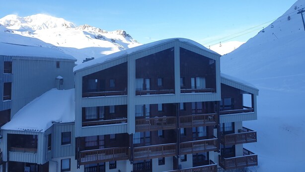 A multi-story hotel with balconies, set against a snowy mountain backdrop. - Studio cabin at the slopes, pets allowed (Tignes)