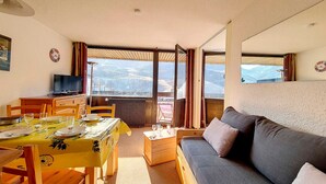 A cozy living room with a sofa, dining table, and a TV. - Bright 2-Room Apartment - Ski-in/Ski-out - Balcony - 6 ppl - Wifi (Les Menuires)