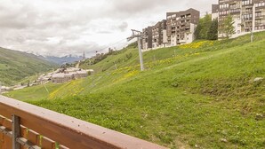 A hillside with a building complex, a wooden fence, and a cable car system. - Functional studio, ski-in/ski-out, balcony (Les Menuires)