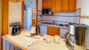 Une cuisine compacte dotée de meubles en bois, d’un four à micro-ondes, d’une cuisinière et d’une machine à café.