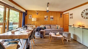 A cozy cabin interior with a wooden dining table, a sofa, and a kitchen area. - Bright 3-room apartment near slopes with balcony (Saint-Martin-de-Belleville)