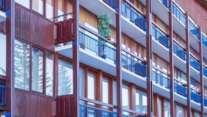 Een meerlaags gebouw met balkons, houten lambrisering en grote ramen.