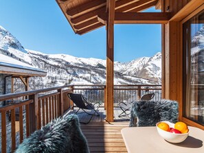 Una terraza de madera con vistas a montañas nevadas.