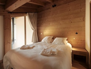 Ein Schlafzimmer mit Holzwandverkleidung, einem Bett, Kissen und einem Nachttisch.