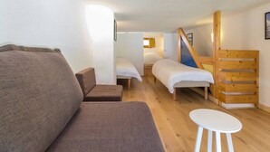 Una habitación acogedora con un sofá, una mesita y dos camas.