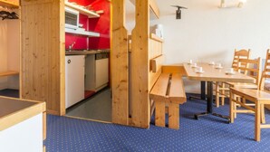 A compact room with a kitchenette, wooden furniture, and a dining area.