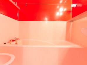 Ein modernes Badezimmer mit einer großen Badewanne, einem sichtbaren Duschbereich und einem Waschbecken.