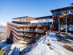 A multi-story hotel with balconies and a ski resort backdrop. - Cozy central studio, balcony, Wi-Fi, sleeps 5 (Les Arcs 1800)