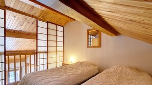 A bedroom with two beds, wooden ceiling beams, a large window, and a mirror on the wall. - Spacious Duplex 8 pers · Ski-in/Ski-out · Balcony (Saint-Martin-de-Belleville)