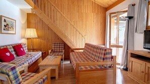 A cozy living room with wooden furniture, a staircase, and a television. - Spacious Duplex 8 pers · Ski-in/Ski-out · Balcony (Saint-Martin-de-Belleville)