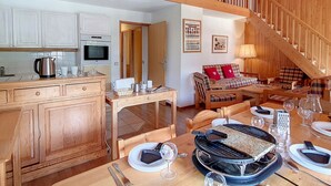 A spacious kitchen with wooden cabinets, a dining area with a table set for four, and a staircase leading to an upper level. - Spacious Duplex 8 pers · Ski-in/Ski-out · Balcony (Saint-Martin-de-Belleville)