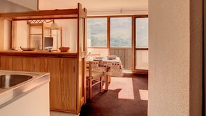 A kitchen with wooden cabinets, a sink, and a dining area with a table and chairs.