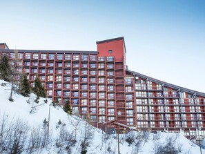 A large hotel with multiple floors and balconies, situated on a snowy hillside.