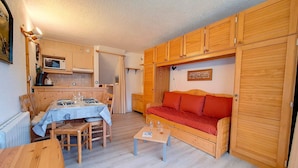 Un espacio habitable compacto con comedor, kitchenette y sofá.
