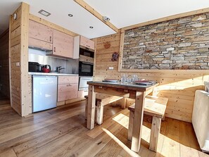 Kompakti keittiö, jossa on puukaapit, sisäänrakennettu uuni ja pieni jääkaappi.