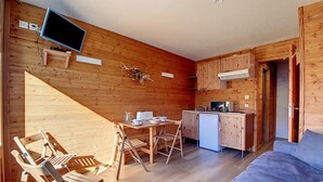 A compact wooden cabin with a dining area, kitchenette, and a sofa.