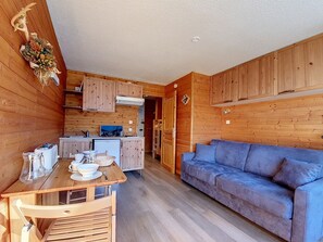 Une petite cabane en bois comprenant un coin cuisine, un espace repas et un canapé.