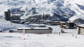 A snow-covered ski resort with buildings, ski slopes, and a mountain backdrop.