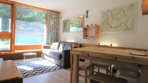 Un salon moderne avec une grande fenêtre, un canapé, une table à manger et une carte accrochée au mur.