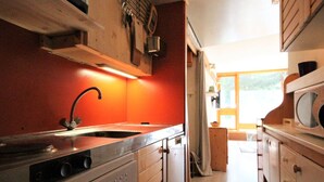 Une cuisine de taille réduite, équipée d’un évier, d’une cuisinière et d’un four à micro-ondes.
