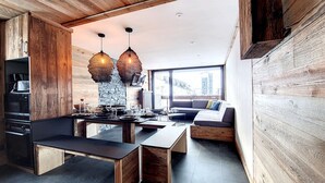 A modern kitchen with wooden accents, a dining area with a bench, and a large window offering a city view.