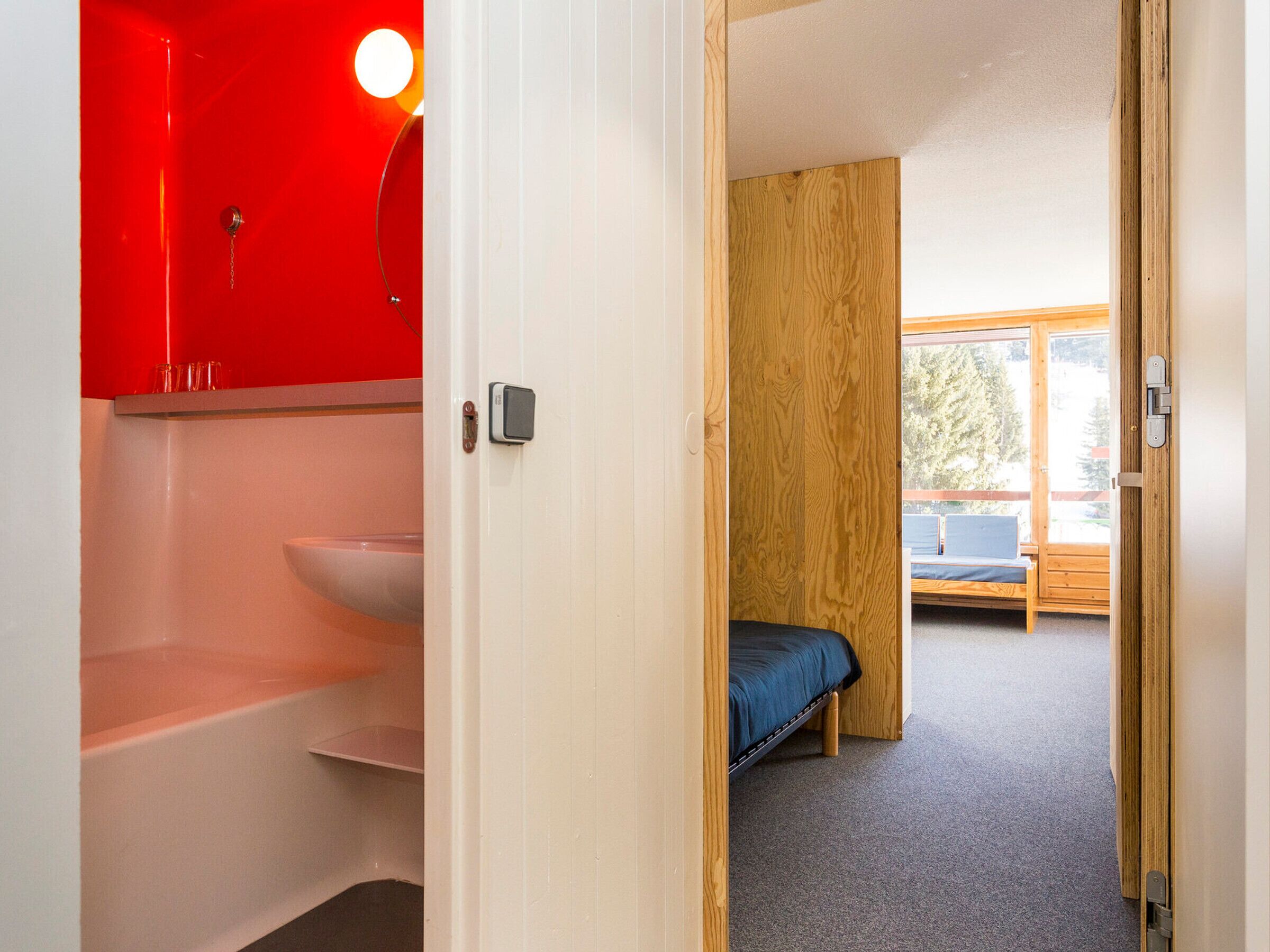 A room with a bed, a wooden wall, and a red cabinet.