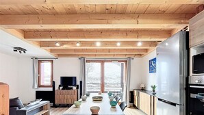 Una cucina moderna con zona pranzo, soffitto in legno e ampie finestre.