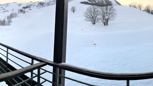 Paesaggio montano innevato con una ringhiera metallica in primo piano.