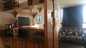 Un salon chaleureux avec un meuble en bois, un téléviseur et un canapé à motifs écossais.