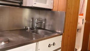 A compact kitchen with a stainless steel sink, a microwave, and a stove. - Cozy ski-in/ski-out studio with balcony (Les Arcs 1800)