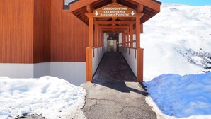 A wooden building with a covered entrance and a sign indicating it is a public ascender. - Renovated studio at slopes, balcony, sleeps 4, Les Menuires (Les Menuires)
