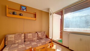 Een gezellige woonkamer met een bank, een houten salontafel en een raam met uitzicht op een besneeuwd landschap.
