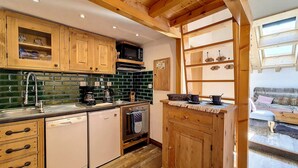 A kitchen with wooden cabinets, a microwave, and a coffee maker. - 2-room apartment at the foot of the slopes, village center (Saint-Martin-de-Belleville)