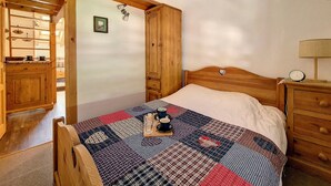 A bedroom with a wooden bed, a nightstand, a wooden wardrobe, and a quilt on the bed. - 2-room apartment at the foot of the slopes, village center (Saint-Martin-de-Belleville)