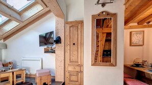A cozy room with a wooden ceiling, a large wooden cabinet, a small table with a red tablecloth, and a bench. - 2-room apartment at the foot of the slopes, village center (Saint-Martin-de-Belleville)
