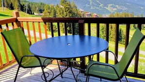 Eine Terrasse mit einem runden Tisch und zwei Stühlen, mit Blick auf eine Berglandschaft.