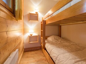 A bunk bed room with wooden walls and a small bedside table with a lamp.