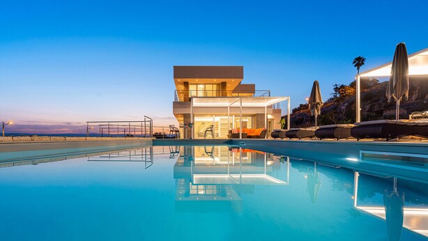 A modern hotel with a pool, outdoor seating, and a view of the landscape.