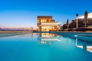 Ein modernes Hotel mit Pool, Sitzgelegenheiten im Freien und Blick auf die Landschaft.