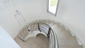 A spiral staircase with a metal railing and clear glass fixtures.