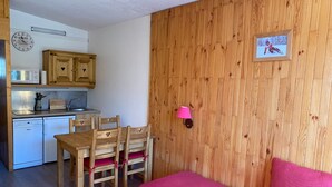 A compact living space with a kitchenette, wooden furniture, and a cozy bed. - Cozy Studio · Ski-In/Ski-Out · Balcony · Mountain Views (Les Arcs 1800)